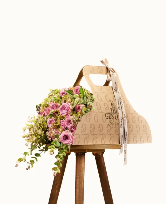 Woven straw tote bag with tassel on wooden stand, pink flowers draped over side