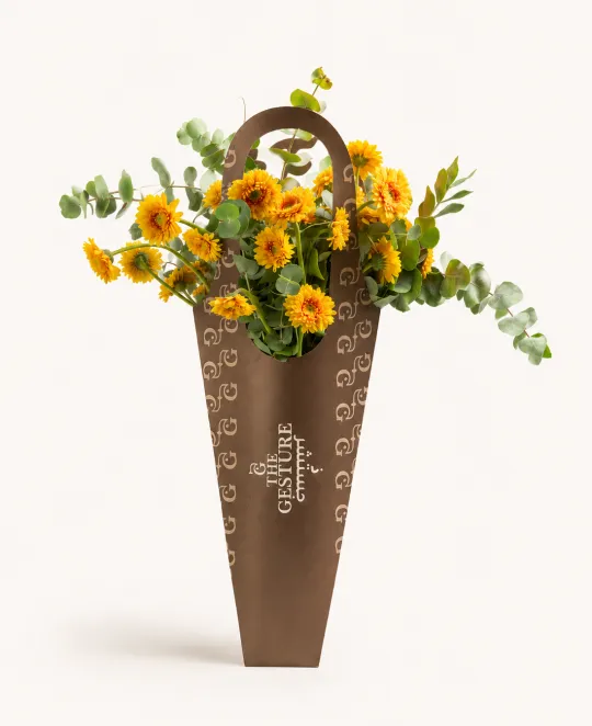 Yellow and orange floral arrangement in a tall brown woven basket vase
