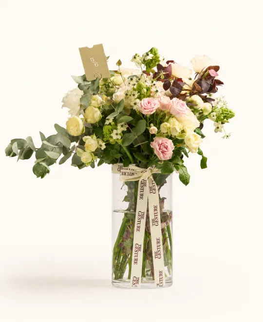 Mixed floral arrangement with pink roses, white flowers, and greenery in clear glass vase