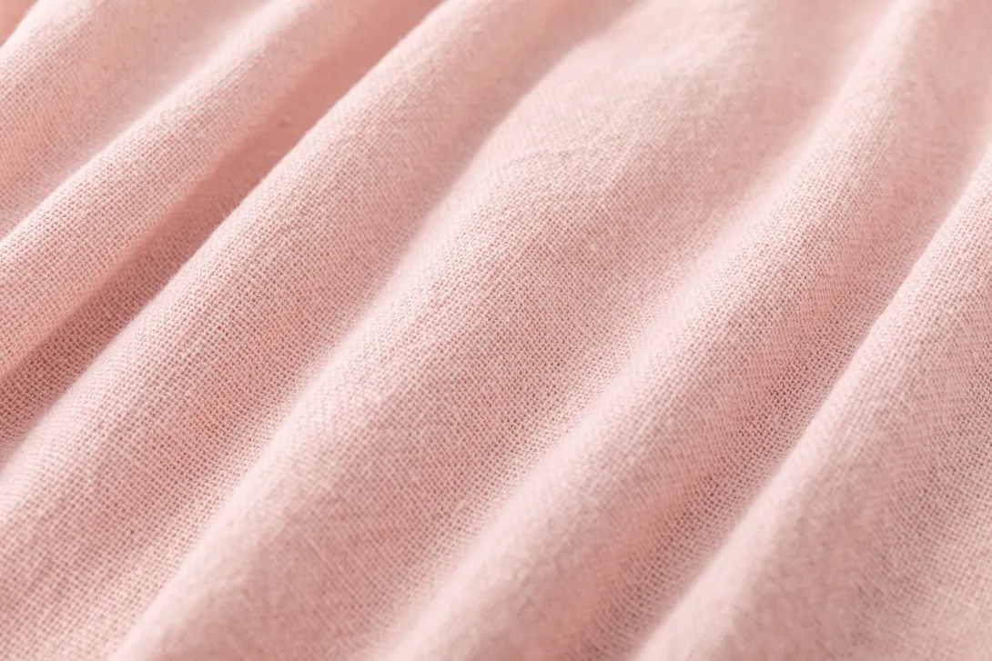 Close-up of soft pink ribbed fabric texture with diagonal folds