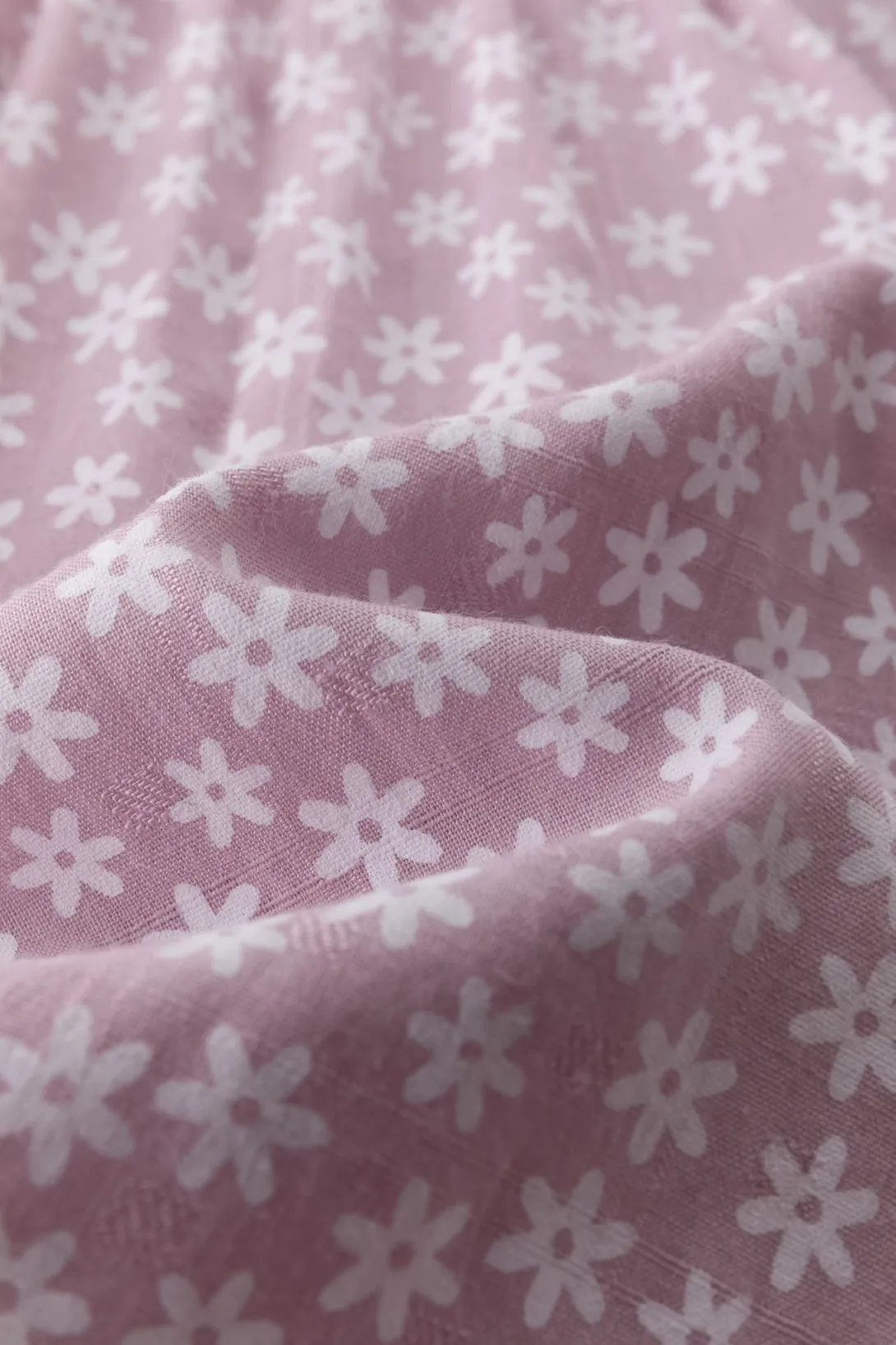 Pink fabric with white floral pattern in soft folds