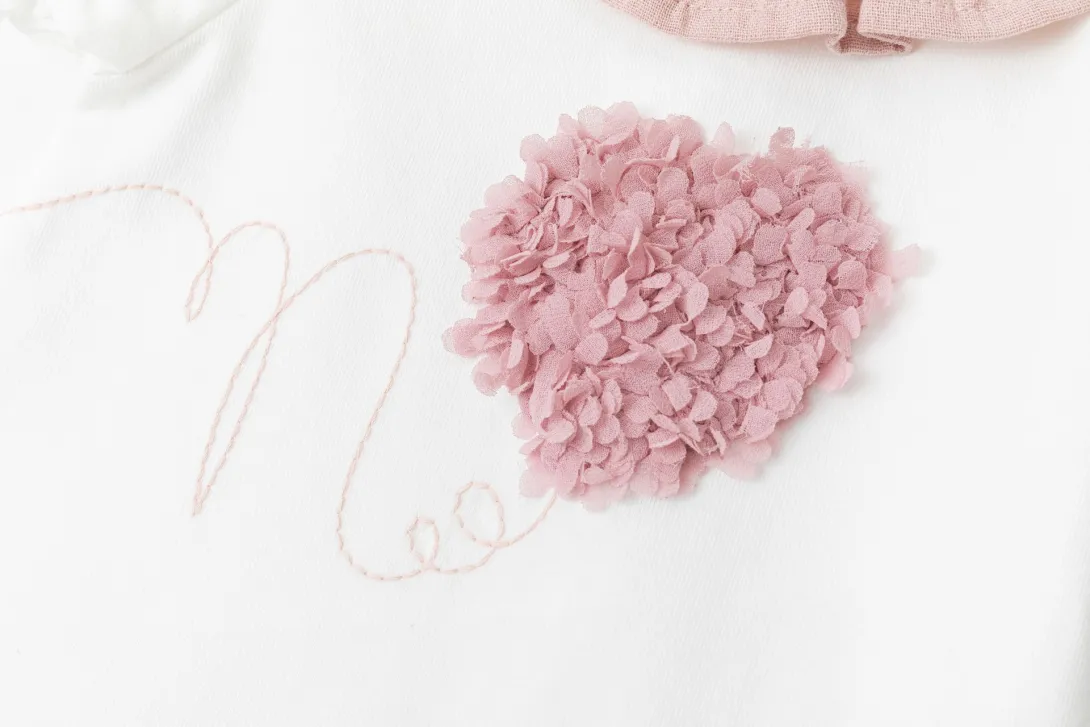 Pink fluffy pom-pom with clear elastic hair ties on white surface