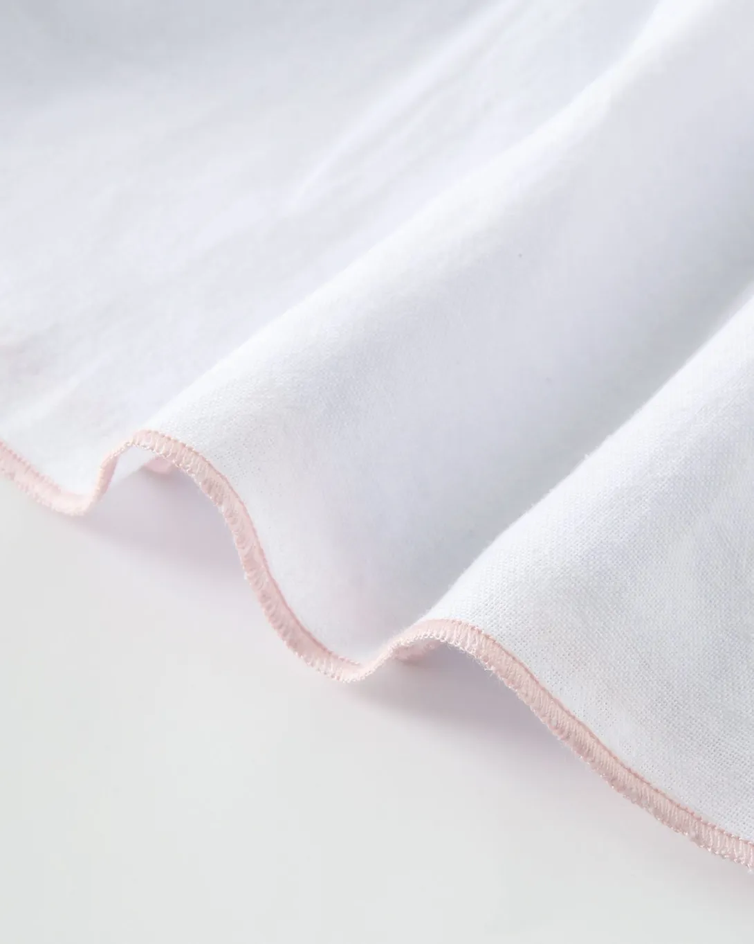 White fabric with delicate pink scalloped edge trim