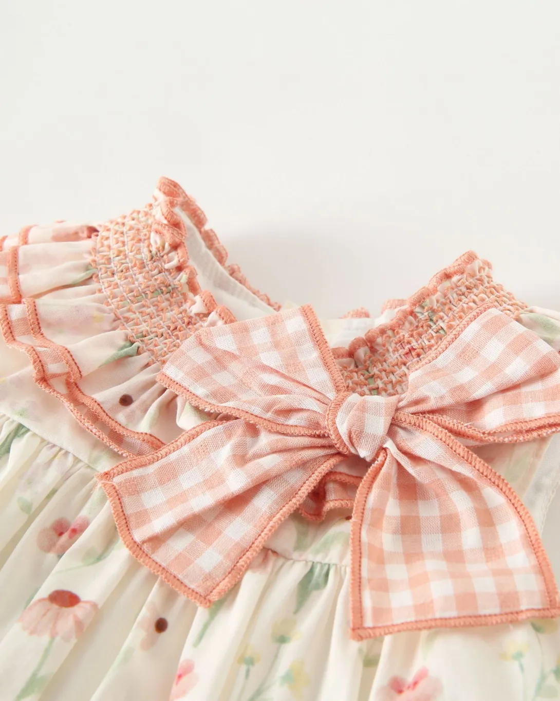 White dress with pink gingham ribbon bow and floral embroidery detail