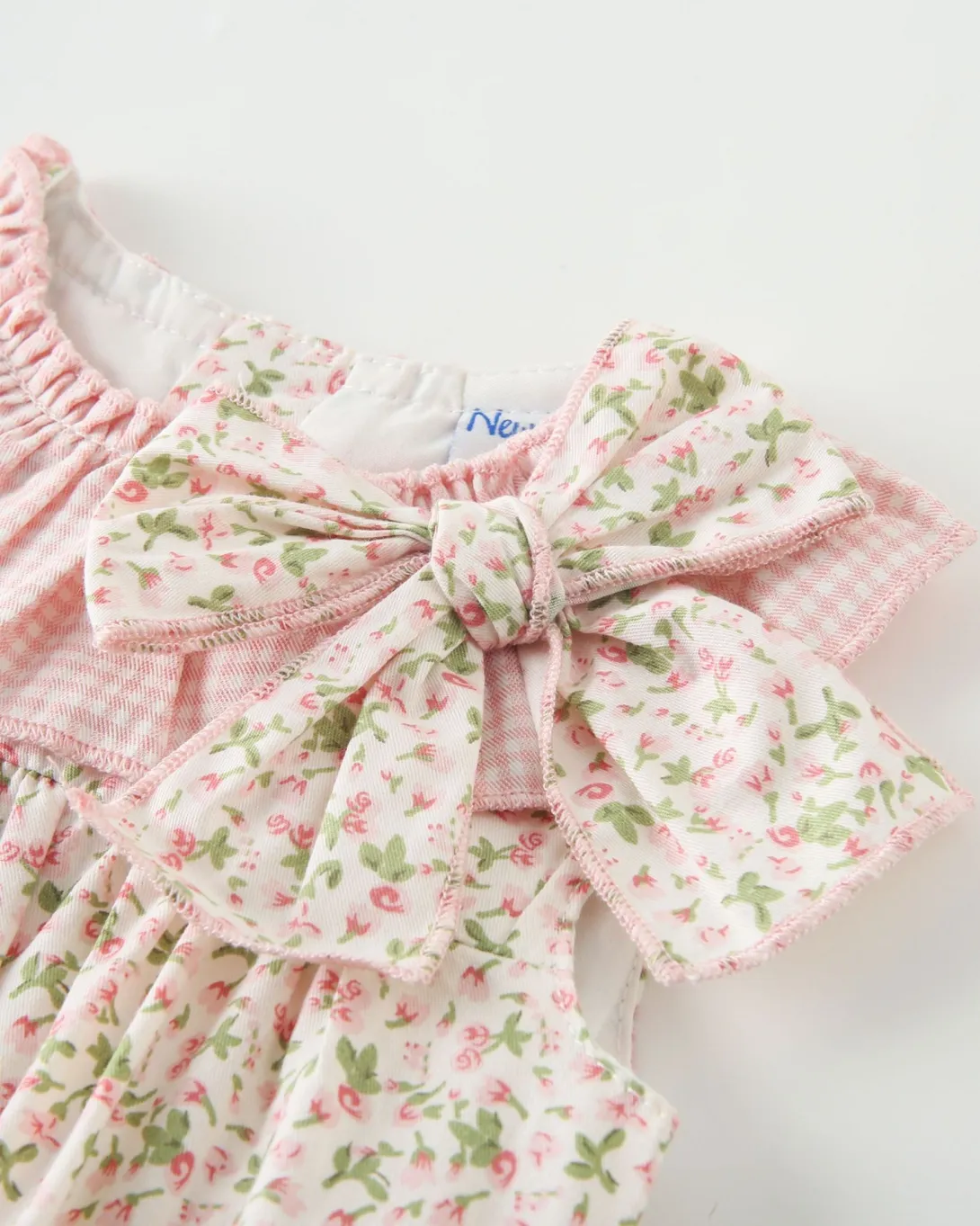 Pink gingham and floral print dress with large bow detail at shoulder