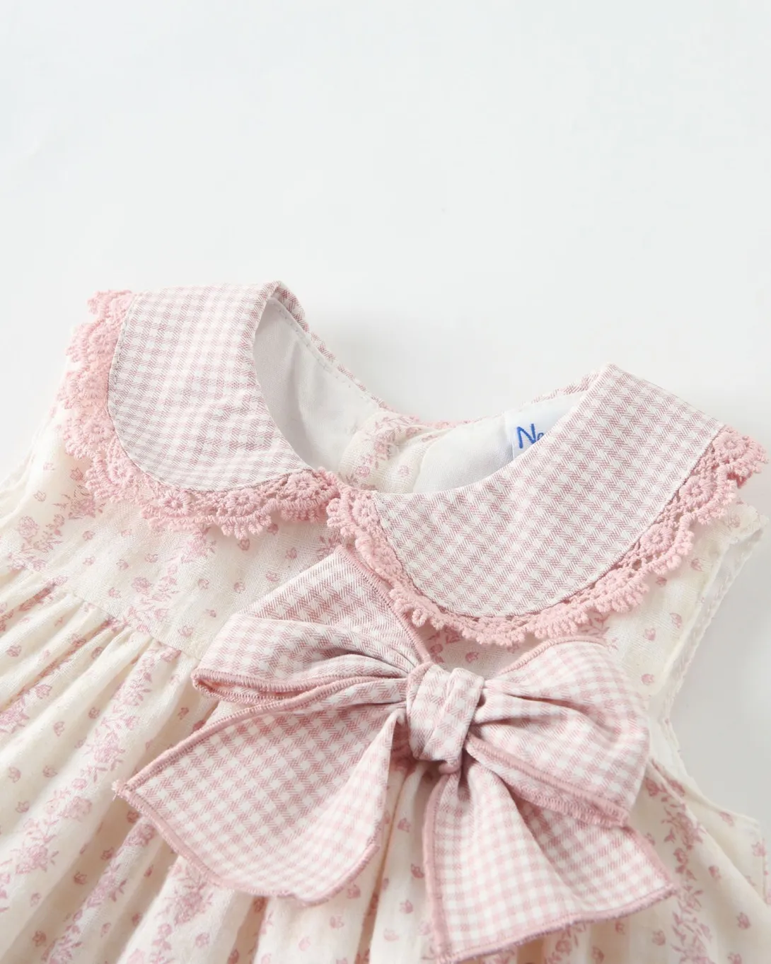 White baby dress with pink gingham collar and bow detail