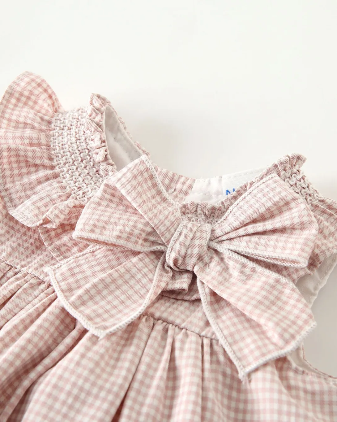 Pink gingham baby dress with white eyelet trim and bow detail