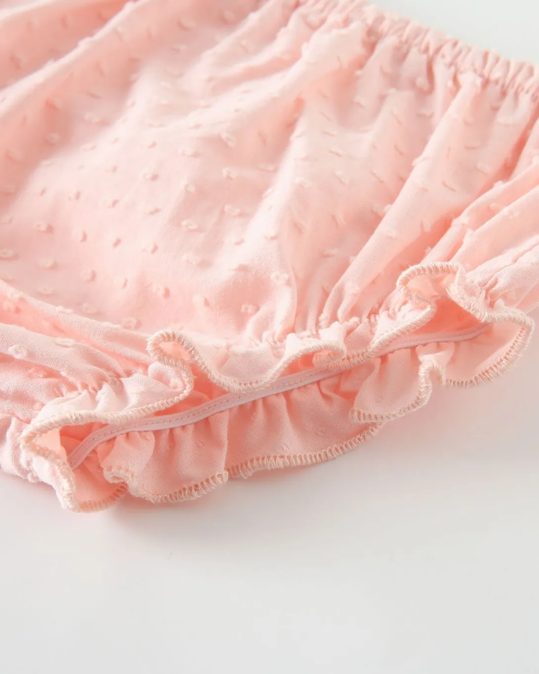 Light pink ruffled shorts with elastic waistband and decorative hem trim