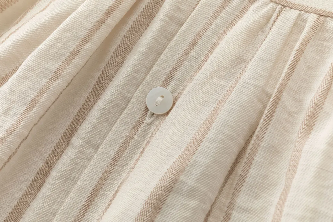 Close-up of beige pleated tulle fabric with a decorative pearl button detail