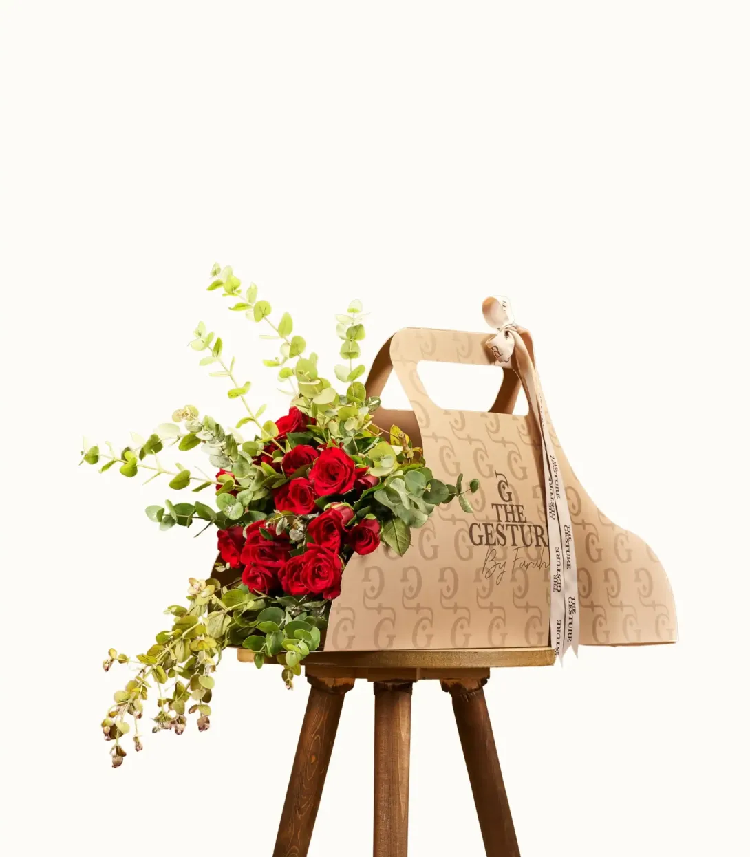Natural woven tote bag with red flowers and greenery hanging on wooden stand