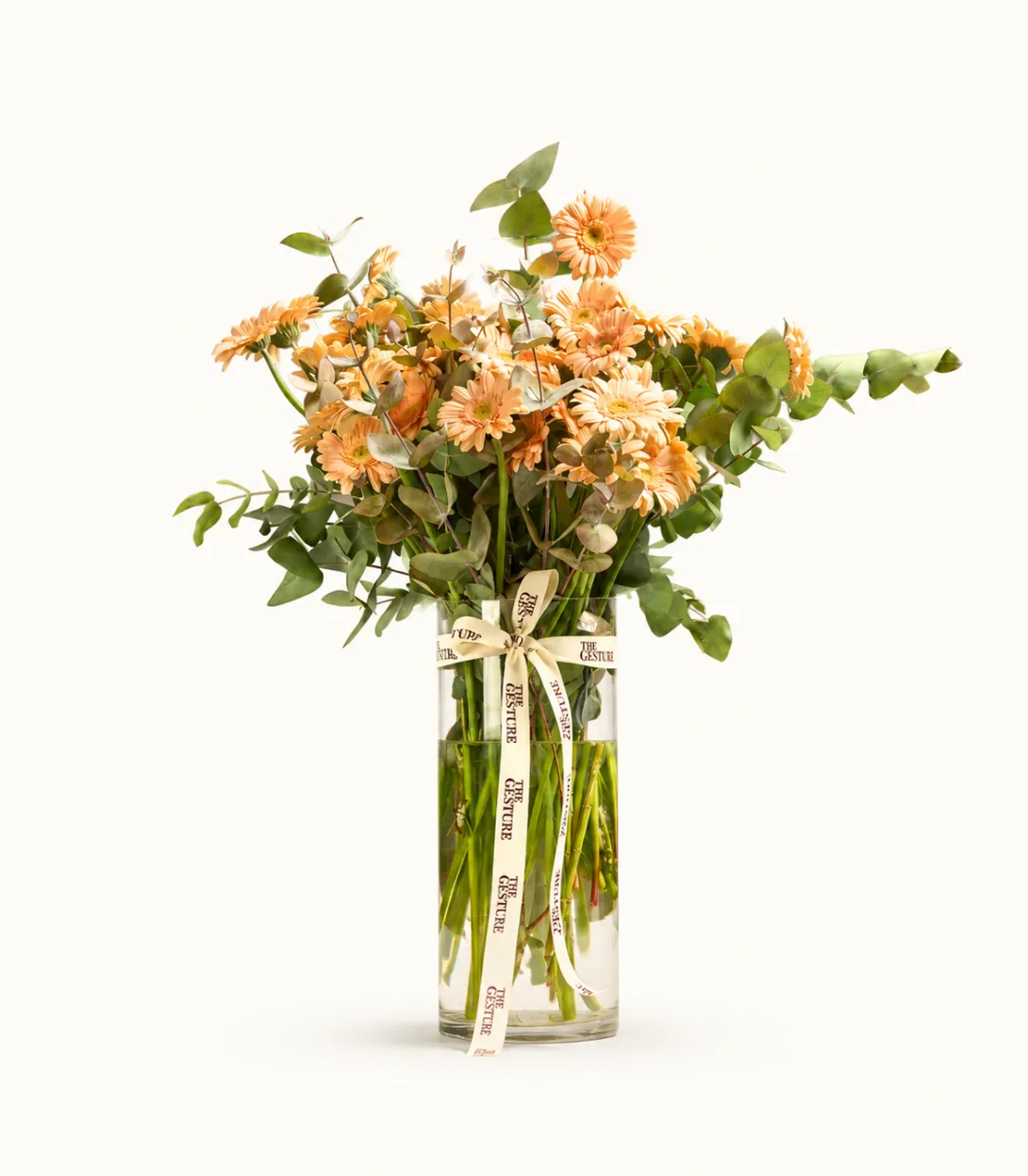 Bouquet of peach and cream roses with greenery in clear glass vase