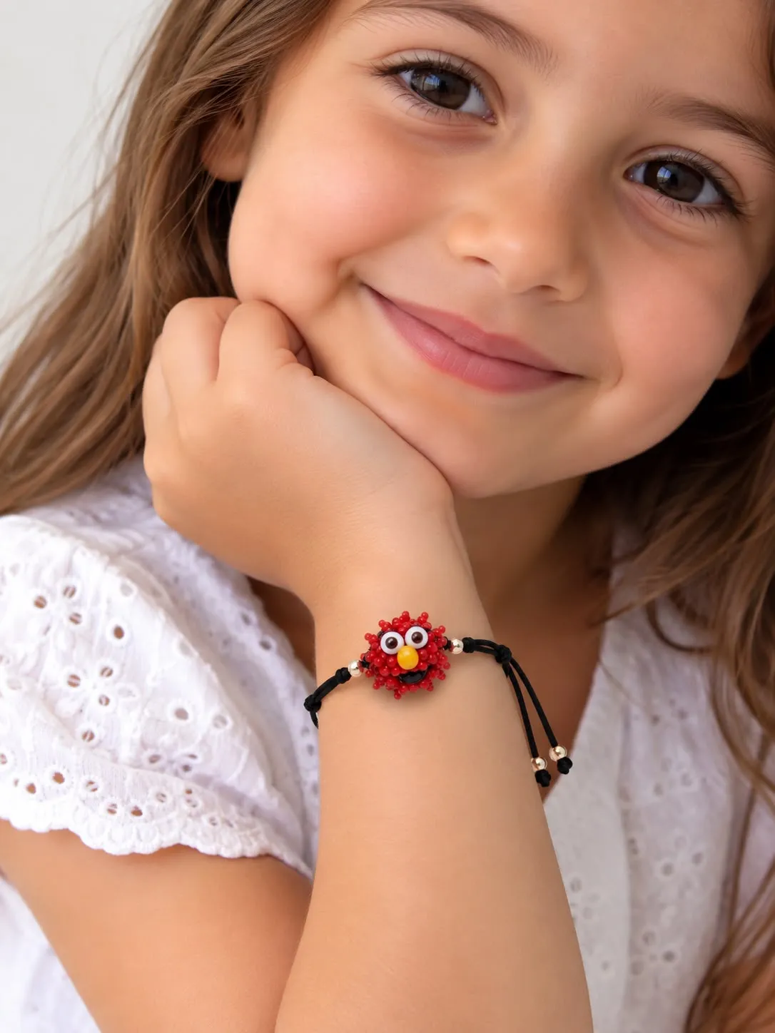 Girl wearing red beaded bracelet with white eyelet top