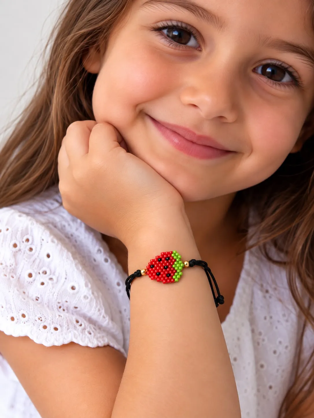 Girl wearing a colorful beaded bracelet with rainbow colors and a heart charm
