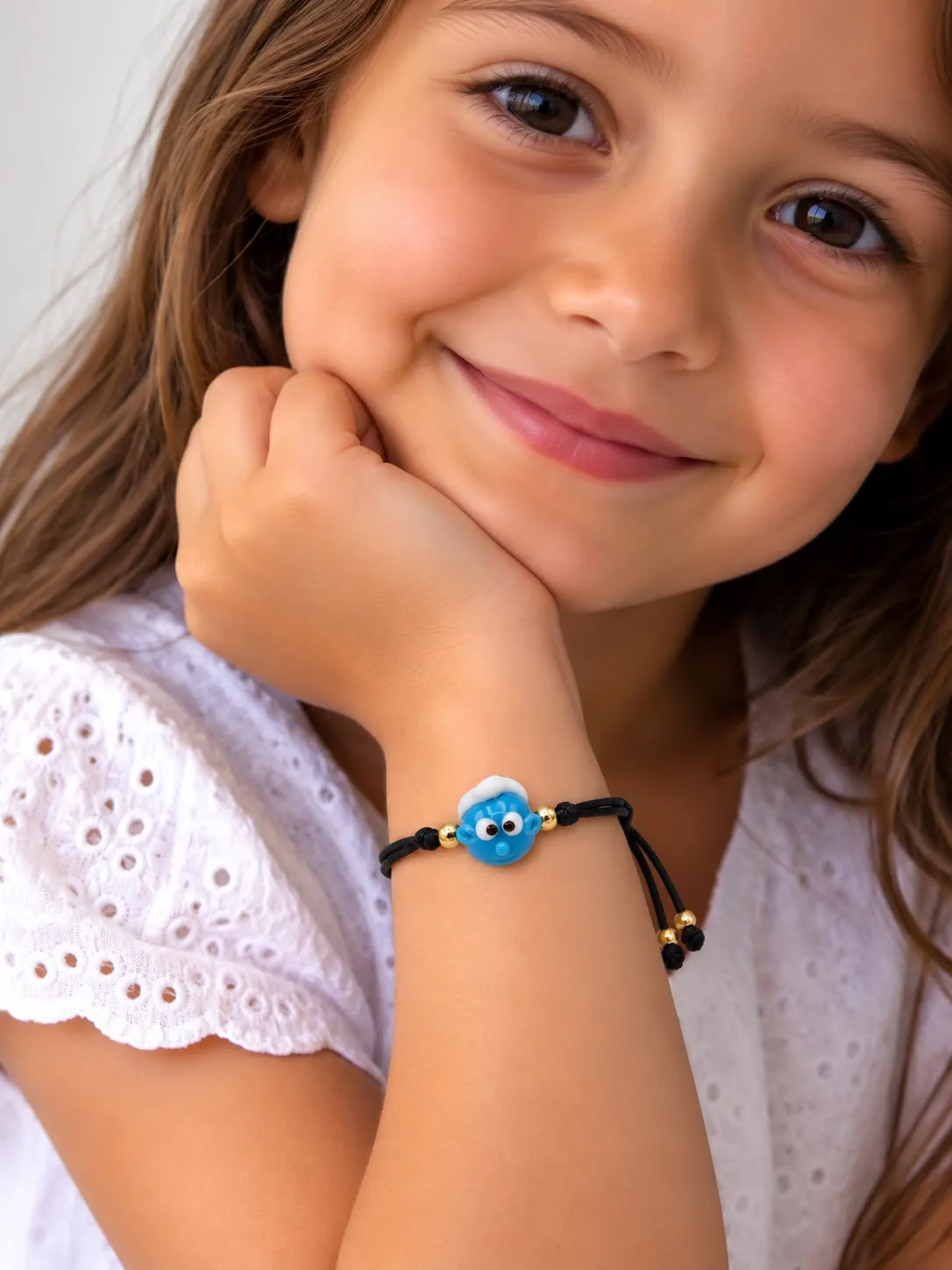 Young girl wearing blue beaded bracelet with eye charm detail