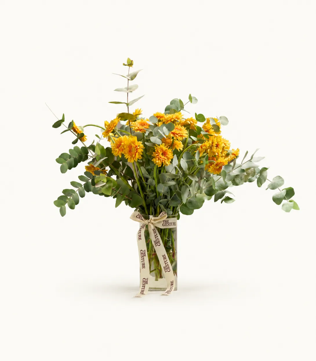 Floral arrangement with yellow and orange flowers and eucalyptus in a clear glass vase