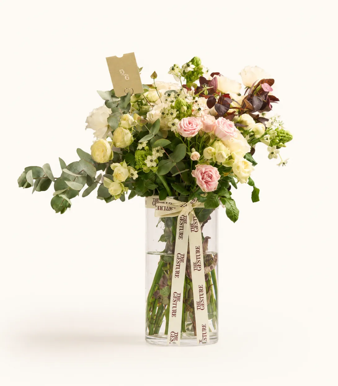 Mixed floral arrangement with pink roses, white flowers, and greenery in clear glass vase